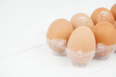 Close-up view of raw chicken eggs in egg box on white wooden background Stock Photos