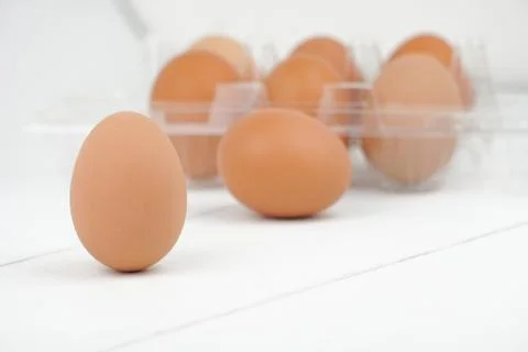 Close-up view of raw chicken eggs in egg box on white wooden background Stock Photos