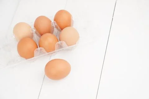 Close-up view of raw chicken eggs in egg box on white wooden background Stock Photos