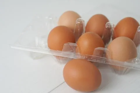 Close-up view of raw chicken eggs in egg box on white wooden background Stock Photos