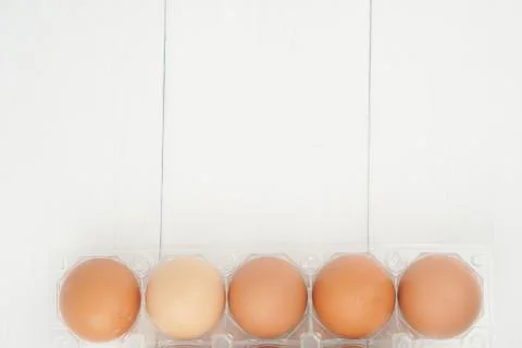 Close-up view of raw chicken eggs in egg box on white wooden background Stock Photos