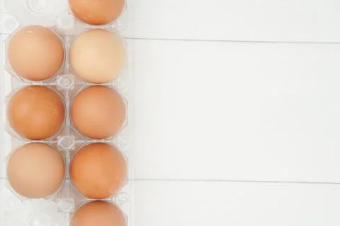 Close-up view of raw chicken eggs in egg box on white wooden background Stock Photos