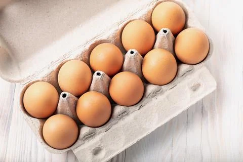 Close-up view of raw chicken eggs in egg box on white wooden background Stock Photos