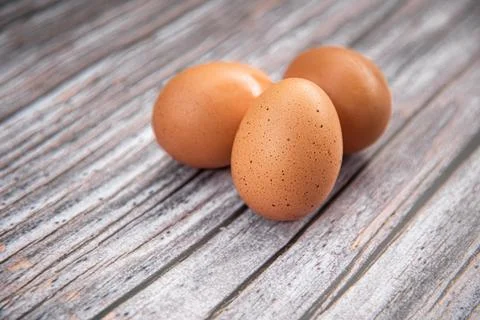 Close-up view of raw chicken eggs on wooden background. Eggs are often said t Stock Photos