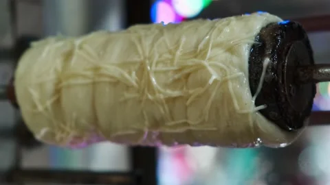 Close view of raw trdelnik, a spit cake, cooking in a store. Cooking in the oven Vidéo 146509977