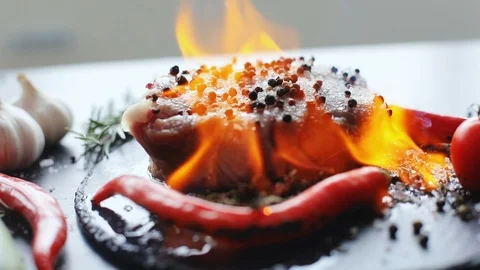 Close-up view of raw uncooked slice of meat and fresh vegetables with flames Stock Footage 86517929