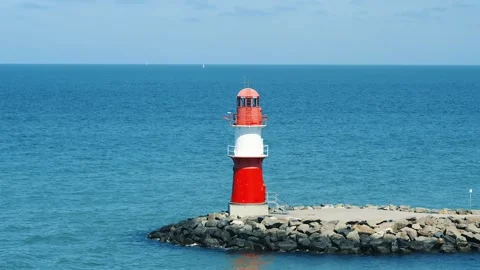Close view of a red and white lighthouse on a rock breakwater at Warnemunde in Video stock 345112860