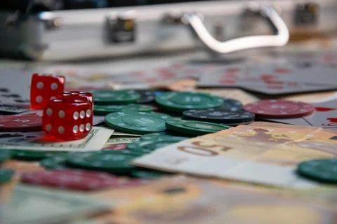 A close-up view of red dice, poker chips, and Euro banknotes scattered on a t Stock Photos
