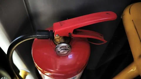Close up view of a red fire extinguisher handle and pressure gauge. Stock Photos