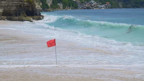 Close up view of a red flag on a tropical beach with beautiful bright water Video stock 115021215
