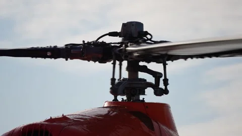 Close-up view of a red helicopter main rotor assembly in motion and coming to Stock Footage 316782558