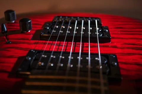 Close-up view of a red modern electric guitar with dark wood grain patterns.. Stockfoto's