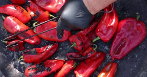 A close-up view of red peppers being roasted for making ajvar. Hand of elderly p Stock Footage 207723526