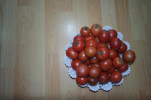 Close-up view of red tomatoes in white basket on a wooden floor in market Stock Photos