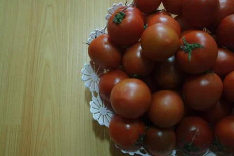 Close-up view of red tomatoes in white basket on a wooden floor in market Stock Photos