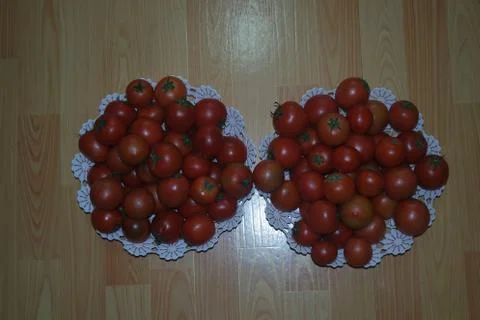 Close-up view of red tomatoes in white basket on a wooden floor in market Stock Photos