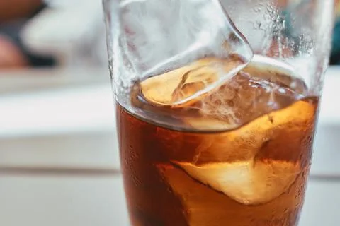 A close-up view of a refreshing dark carbonated beverage with melting ice cub Fotos Stock