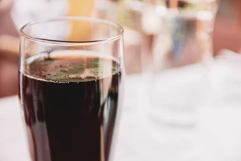 Close-up view of a refreshing dark soft drink in a tall glass cup on a table Stock Photos