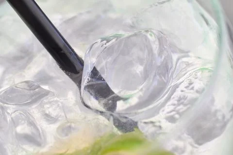 Close-up view of a refreshing gin and tonic cocktail with ice cubes and straw 스톡 사진