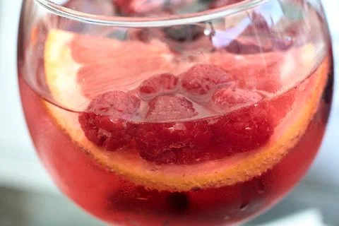 Close-up view of a refreshing pink gin cocktail garnished with fresh raspbe.. Stock Photos