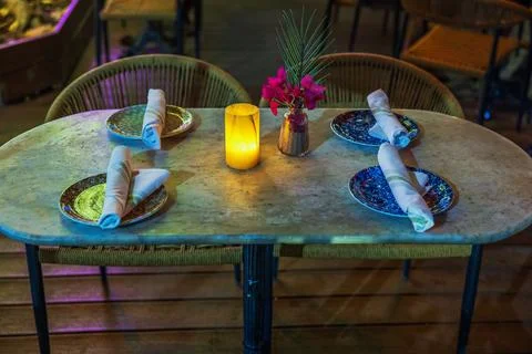 Close-up view of restaurant table set for four with plates, napkins, candle Stock Photos