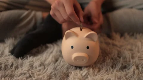 Close-up view revealing hand carefully inserting coins into pink piggy bank.. Stock Footage 306949593