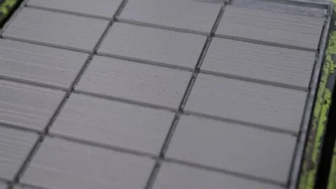 Close view of ribbed grey tile sheets sliding along the worn green rails of a Stock Footage 346738000