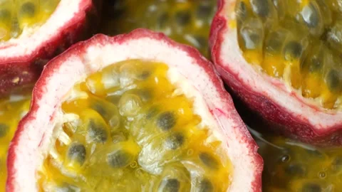 Close up view of ripe passion fruit halves turning on textured fruit background. Stock Footage 345639855