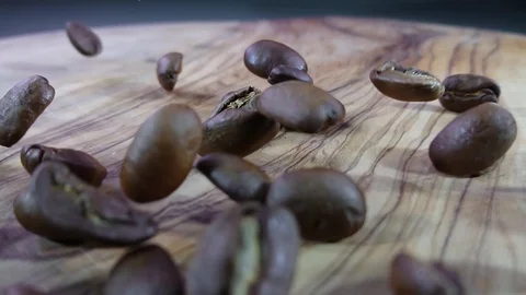 Close-up view of roasted coffee beans falling down on the wooden board Stock Footage 127651878