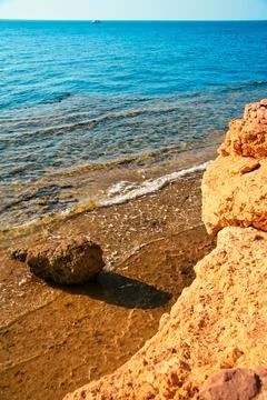 Close view of a rocky beach with soft waves washing ashore, highlighting na.. Stock Photos