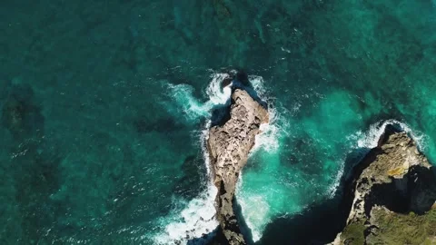 Close-up view of rocky coastline captures vibrant hues of ocean waters swirling Stock Footage 272160708