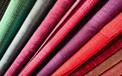 Close up view of rolled fabric textiles in various colors and textures Stock Photos