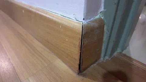 A close-up view of a room corner showing a damaged wooden skirting. Vidéo 322032507