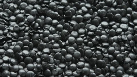 Close view of rotating black polyethylene granules creates dense plastic texture Stock Footage 334657509