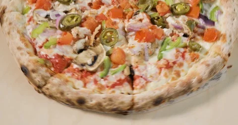 Close-up view of rotating half tasty pizza with bacon and vegetables on light Stock Footage 105307875