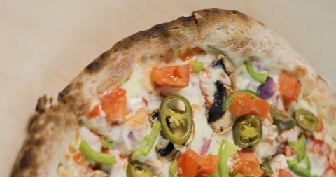 Close-up view of rotating half tasty pizza with bacon and vegetables on light Vídeos de archivo 105307975