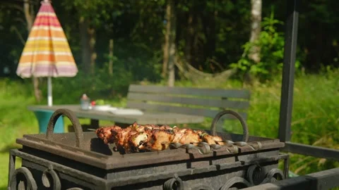 Close-up view of rotating meat skewers on outdoor grill in backyard Stock Footage 339135003