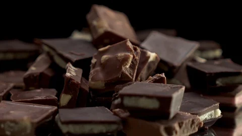 Close up view on rotating pieces of chocolate on the table with black background Stock Footage 124280600