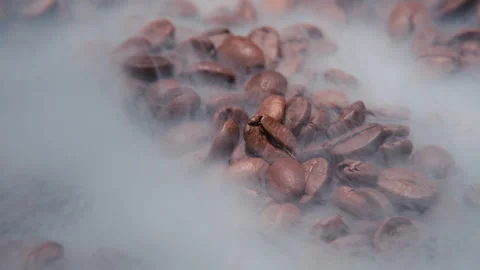 Close-up view of rotating roasted coffee beans, with the beans spinning in smoke Stock Footage 286772636