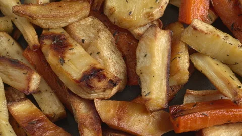 Close-up view of rotating roasted parsnip and carrot roots. Video stock 327453698