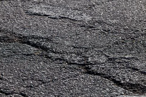 Close-Up View of Rough Asphalt Surface Highlighting Its Textured and Cracke.. Stock Photos