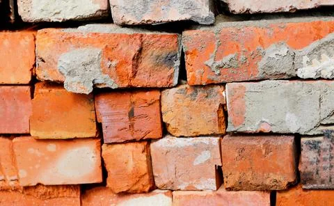 A close-up view of a rough, weathered brick wall. The red and orange clay b.. Stock Photos