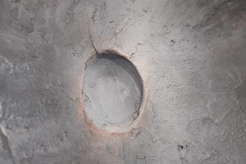 Close-up view of a round hole in a textured grey concrete surface Stock Photos