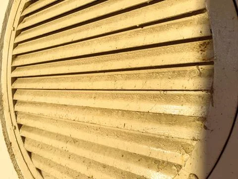 Close view of a round vent with horizontal slats shows wear and dirt in a b.. Stock Photos