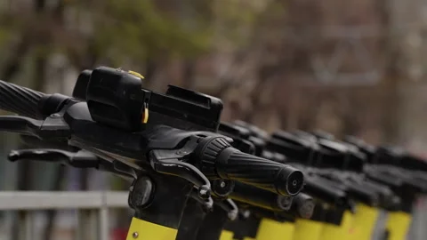 Close-up view of a row of yellow electric scooters along a city sidewalk Stock Footage 317561501