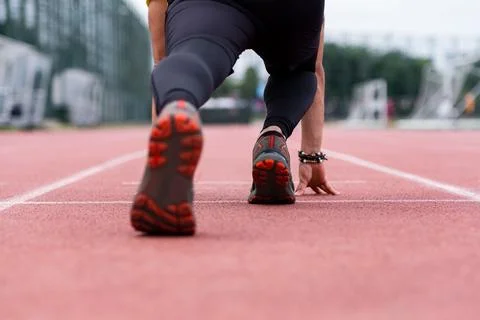 Close-up view of runner legs in a low start position beginning of sprint along Stock Photos