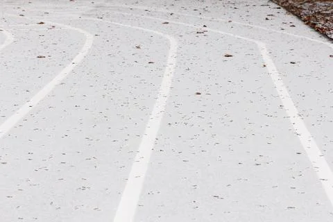 A close-up view of a running track with white lines and scattered leaves Stock Photos