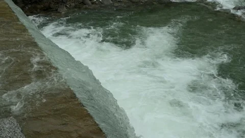 Close-up view of rushing water cascading over a dam. Perfect for concepts of Stock Footage 281536520