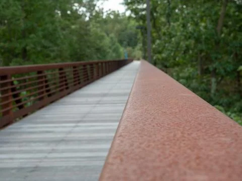 Close view of rusted hand rail along a wooden foot bridge Foto stock