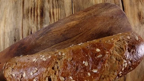 Close up view. Rustic bread with seeds fall on a wooden table Stockbeeldmateriaal 123364798